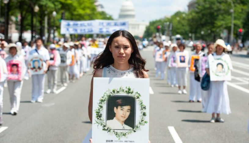 یک زن عکس مردی را در دست دارد که بر اثر آزار و شکنجه تمرین روش معنوی فالون گونگ در چین، به دست حزب کمونیست کشته شده است ( Larry Dye/The Epoch Times )