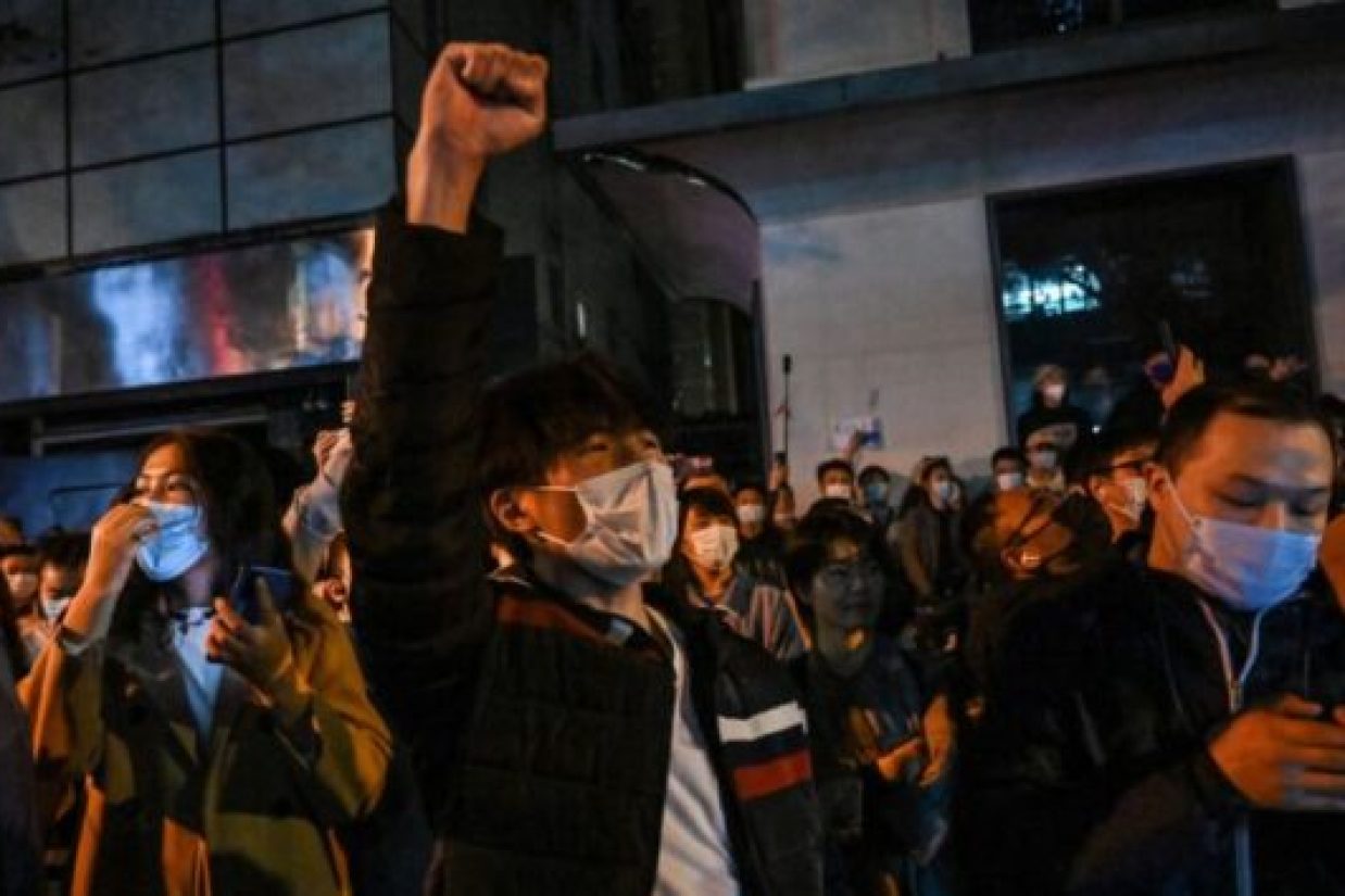 People sing slogans while gathering on a street in Shanghai on November 27, 2022, where protests against China's zero-Covid policy took place the night before following a deadly fire in Urumqi, the capital of the Xinjiang region. (Photo by Hector RETAMAL / AFP) (Photo by HECTOR RETAMAL/AFP via Getty Images)