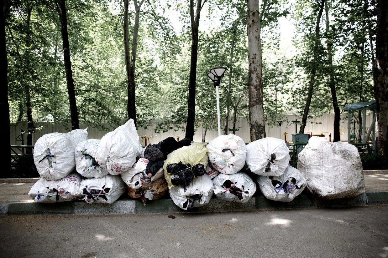 An Iranian scavenger sleeps on a pile of items collected from trash bins as he waits for a vehicle to take them for recycling in northern Tehran on April 12, 2013. AFP PHOTO/BEHROUZ MEHRI        (Photo credit should read BEHROUZ MEHRI/AFP/Getty Images)