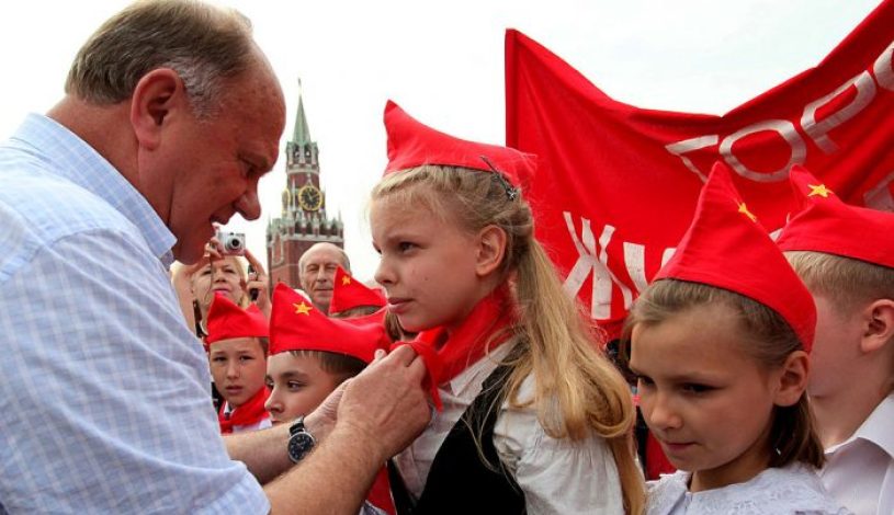 گنادی زیوگانوف ، رهبر حزب کمونیست روسیه دستمال گردن‌‏های قرمز را که نماد آغاز فعالیت آنها در گروه جوانان پیشگام جوان کمونیست است، به گردن کودکان گره می‌‏زند. این گروه در اتحاد جماهیر شوروی برای کودکان ۱۰ تا ۱۴ ساله ایجاد شده است.)  (Alexey SAZONOV/AFP/Getty Images)
