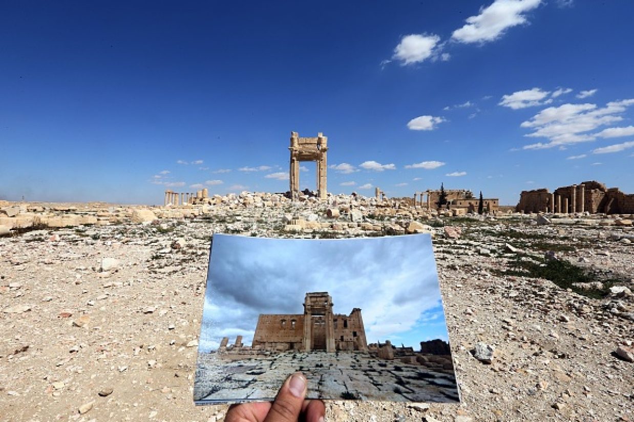 یک عکاس تصویری که از معبد بل واقع در پالمیرا،  در تاریخ ۱۴ مارس ۲۰۱۴ را گرفته است را در مقابل منظره ای که در تاریخ ۳۱ مارس ۲۰۱۶ از آن می‌بیند گرفته است. این مکان تاریخی در سال ۲۰۱۵ توسط تروریست‌های داعش ویران شد. (JOSEPH EID/AFP/Getty Images)