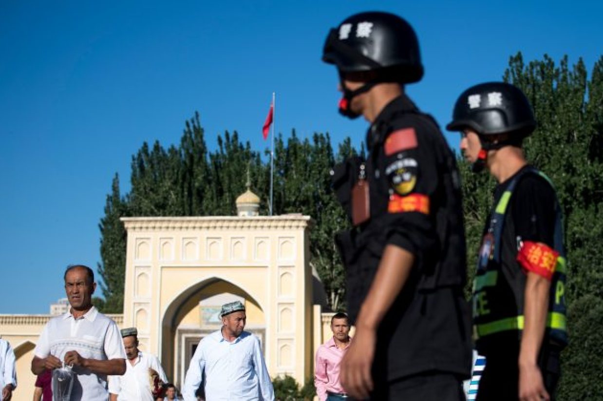پلیس چین، خروج مسلمانان چینی از مسجدی در شهر کاشغر واقع در استان سین‌کیانگ را تحت نظر دارد.  (Johannes Eisele/AFP/Getty Images)